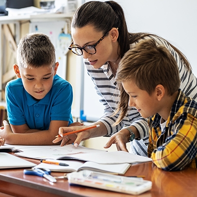 Female teacher reviewing material with young students.