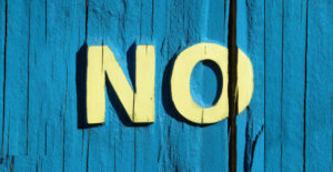 A turquoise wooden wall with the word NO painted on it in light yellow