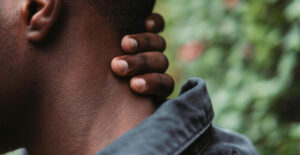 Closeup on the hand of a dark-skinned man as he rubs at his neck