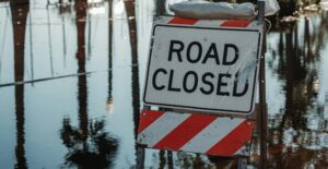 A flooded street with a Road Closed sign