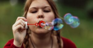 A woman with her hair in braids blows soap bubbles