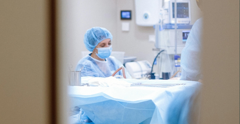 View through the window of a door at surgical prep, with a masked doctor