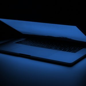A glowing laptop on a dark background. Concerns about tech addition