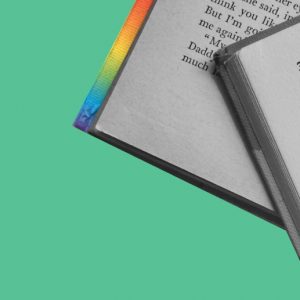 Books with rainbow binding against a green background. Pride reading list