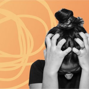 A woman clutching her head in distress against a orange and yellow background. Anxiety attack