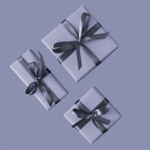 Three wrapped gifts in monochrome on a blue-gray background. Holiday gift guide for people in addiction recovery.