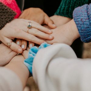 Hands in! A circle of people supporting one another with their hands stacked up.