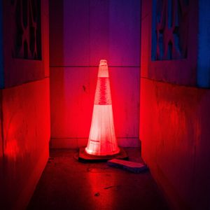 Glowing red safety cone in a dark, dingy corridor.