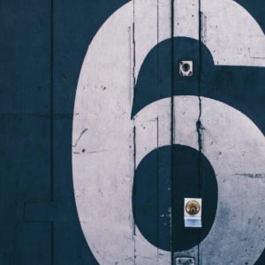 A large number 6 stenciled in white on a dark blue door