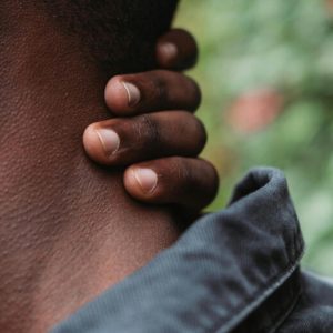 Closeup on the hand of a dark-skinned man as he rubs at his neck