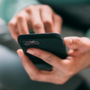 Closeup of hands holding and using a smartphone. The screen is out of view.