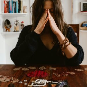 An upset brown-haired woman sits at a table that holds souvenirs of a relationship