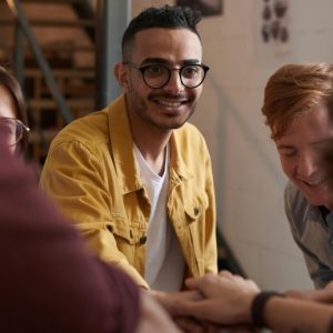 A group of friends laugh and put their hands together in solidarity