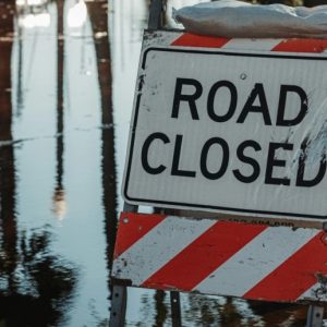 A flooded street with a Road Closed sign