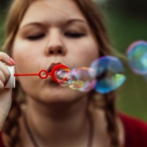 A woman with her hair in braids blows soap bubbles