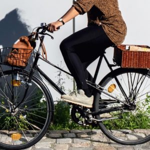 A woman rides a bicycle, her shadow cast on a nearby wall.