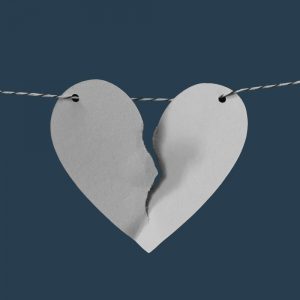 A torn paper heart strong on a horizontal string. Domestic Violence