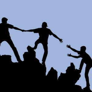 Silhouette of a group helping one another climb a rocky outcrop. Harm reduction