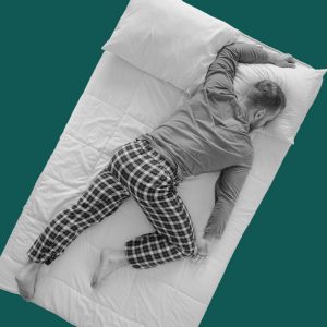 A man sleeping spread face-down across his bed. Treat insomnia without drugs