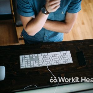 A man stands in front of a computer keyboard and mouse, not touching them