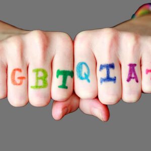 Two fists with LGBTQIA+ written across the knuckles in rainbow colors. Mental Health resources for the LGBTQIA community