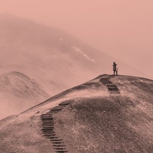 A person stands on a hilltop with stairs below them, cut into the side of the hill. Lessons learned at 10 years of recovery.