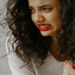 A woman with curly, dark hear grimaces in distaste.