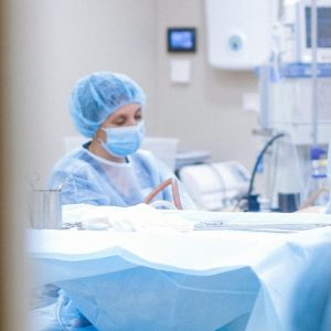 View through the window of a door at surgical prep, with a masked doctor