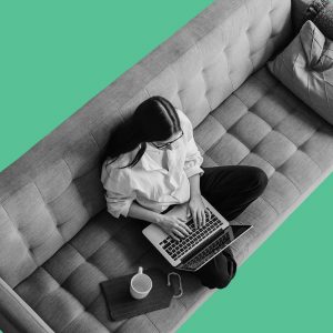 View from above of a woman on a sofa working on a laptop.