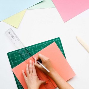 Cutting paper with a ruler and craft knife. Naming Workit Health