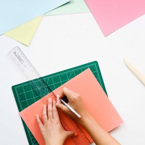 Cutting paper with a ruler and craft knife. Naming Workit Health