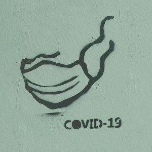 Spray painted art of a face mask and the words COVID-19. Reflecting on a year of COVID