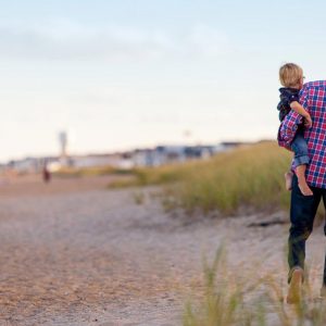 A man on the beach holding a small child on his hip