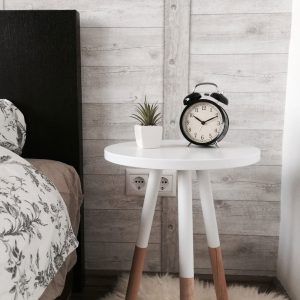 An old fashioned alarm clock on a bedside table beside a potted succulent