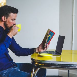 A man reads a book while drinking coffee