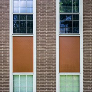 Outside wall of an industrial-looking building, with rows of windows and bricks