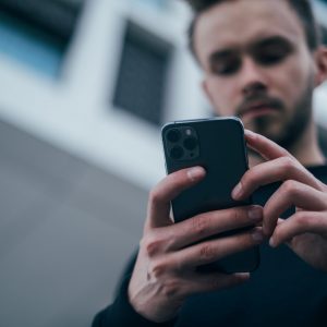 A man looking down at the phone in his hands. Medication assisted treatment