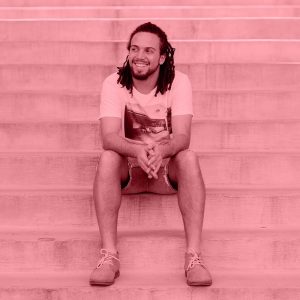 A grinning man sits on the steps to a building