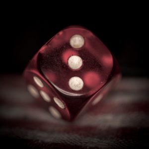 A red plastic die, showing three pips