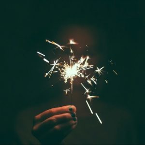 A hand holds a lit sparkler in the dark