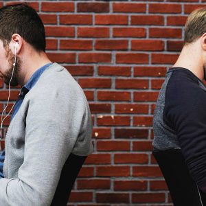 Two men sitting back to back work on laptops. Educate employees about opioids