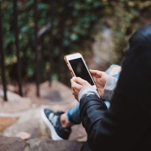 Sitting outdoors, looking at a phone. Priority Health